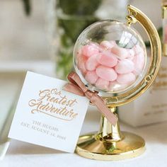 a glass globe with candy in it sitting on a table next to a card holder