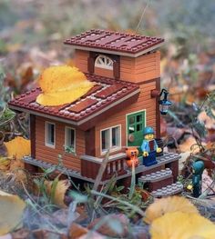 a small toy house sitting on top of leaves