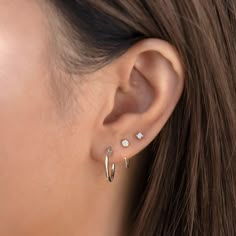 a woman's ear with two small white stones on it