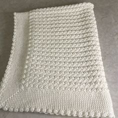 a white knitted blanket sitting on top of a table