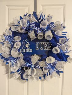 a blue and white wreath with the duke logo on it hanging on a front door