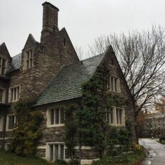 an old stone house with ivy growing on it's roof and two story windows