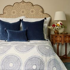 a bed with blue and white bedspread next to a table with flowers on it