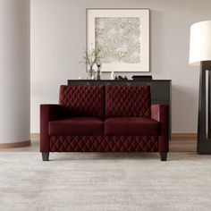 a red couch sitting on top of a white rug next to a lamp and table