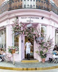 a man standing in front of a pink building with lots of flowers on the outside