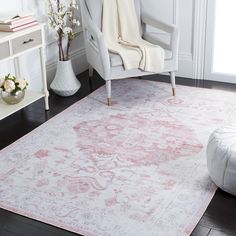 a white chair sitting on top of a hard wood floor next to a pink rug