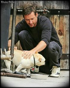 a man kneeling down petting a white dog