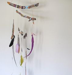 a wind chime with feathers hanging from it's sides on a white wall