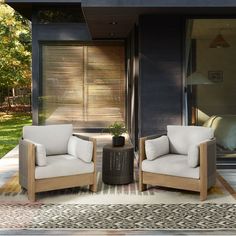 two chairs sitting next to each other on top of a rug in front of a house