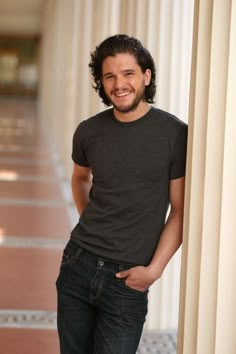 a man standing in front of columns with his hands on his hips and smiling at the camera