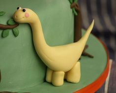 a yellow dinosaur cake sitting on top of a green plate