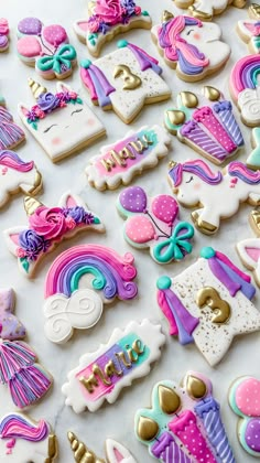 some decorated cookies are laying on a white table top with pink, purple and blue icing