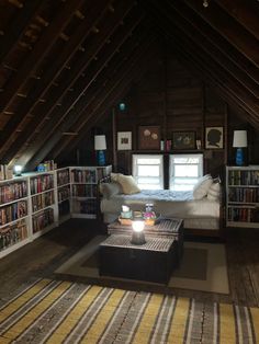 an attic bedroom with bookshelves and a bed in the corner, along with a striped rug on the floor