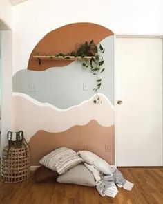 a room with wood flooring and painted mountains on the wall, along with pillows