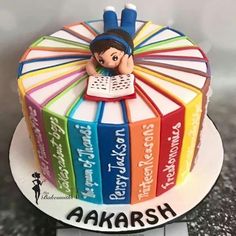 there is a cake that has books on it and the words akarsh written in different languages