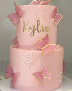 a pink and gold cake with butterflies on it