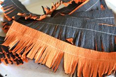 orange and black fringes are hanging from a white plate on a table with utensils