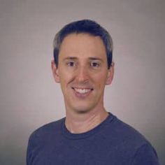 a man in a blue shirt smiling at the camera