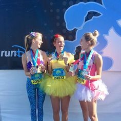 three girls in tutu skirts holding up their medals