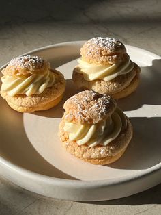 three pastries are sitting on a plate with powdered sugar and cream toppings