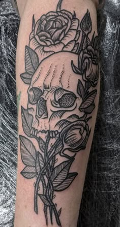 a black and white skull with roses on it's arm, in front of a gray background