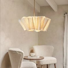 two chairs and a table in a room with a light fixture hanging from the ceiling