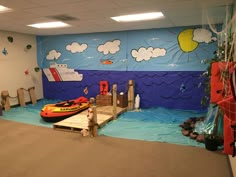 an indoor play area with water toys and life vests on the floor, in front of a painted wall