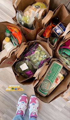 the person is standing on the floor with their feet up in front of some paper bags filled with food