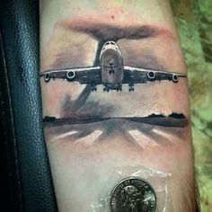 an airplane is flying over the water on this man's arm with a coin