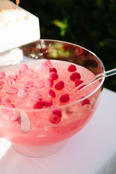 a bowl filled with ice and raspberries sitting on top of a white table