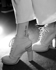 black and white photo of woman's legs with ankle tattoos on her left foot