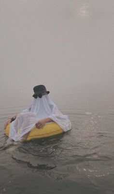 a person floating on top of a yellow raft in the middle of foggy water