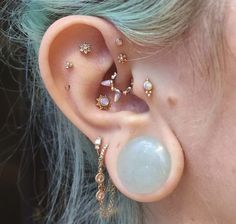 a close up of a person's ear with different piercings on the side