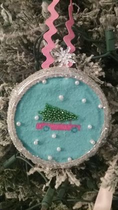 a christmas ornament hanging from a tree with pink ribbon and beads on it