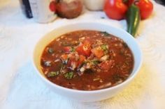 a white bowl filled with soup sitting on top of a table next to some vegetables