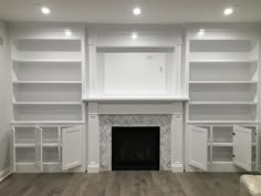 an empty living room with white bookcases and fireplace