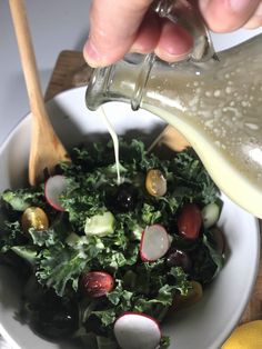 someone pouring dressing into a salad in a bowl