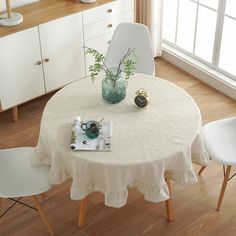 a white table with two chairs and a green vase on top of it in front of a window