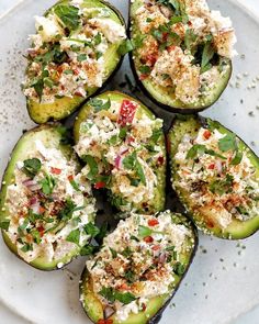 several stuffed cucumbers on a white plate topped with feta cheese and herbs