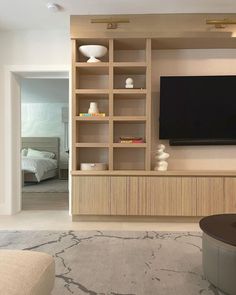 a living room filled with furniture and a flat screen tv mounted on a wall above it