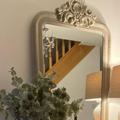 a vase filled with flowers sitting on top of a wooden table next to a mirror