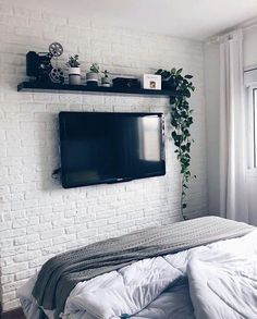 an instagram photo of a bedroom with a flat screen tv on the brick wall