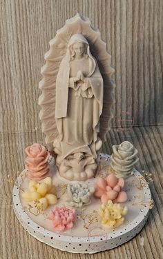 a statue of jesus surrounded by flowers on a white plate with gold trimmings