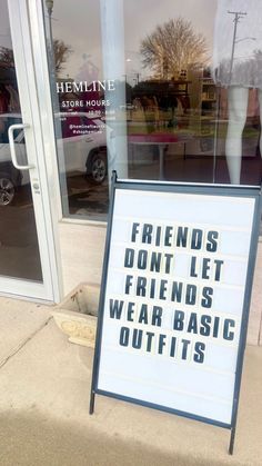 a sign on the sidewalk that says friends don't let friends wear basic outfits