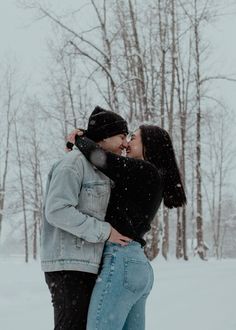 two people standing in the snow kissing each other