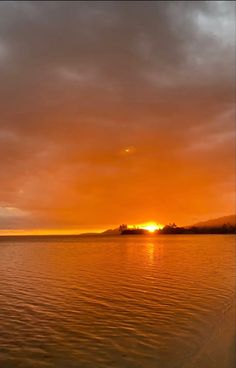 the sun is setting over the water and clouds