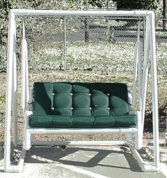 a white swing with green cushions on it