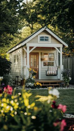 a small white house sitting in the middle of a lush green yard with flowers around it