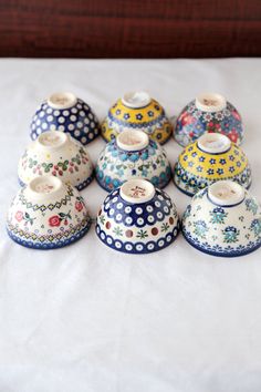 a group of ceramic vases sitting on top of a white tablecloth covered bed