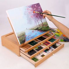 a person holding a paintbrush and painting on an easel